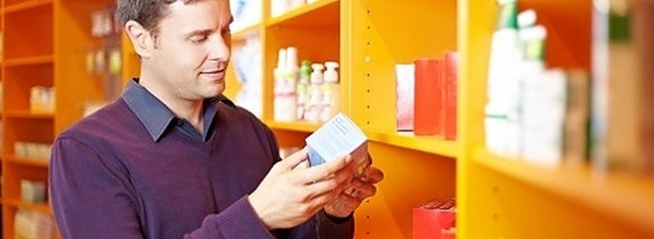Junger Mann in Apotheke betrachtet Medikament