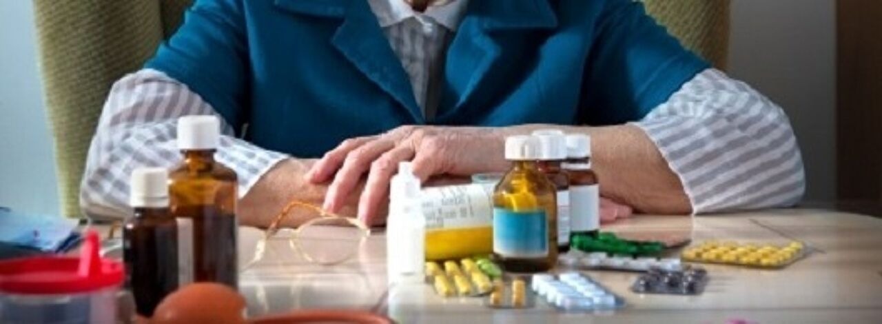 ältere Person vor einem Haufen verschiedener Medikamente