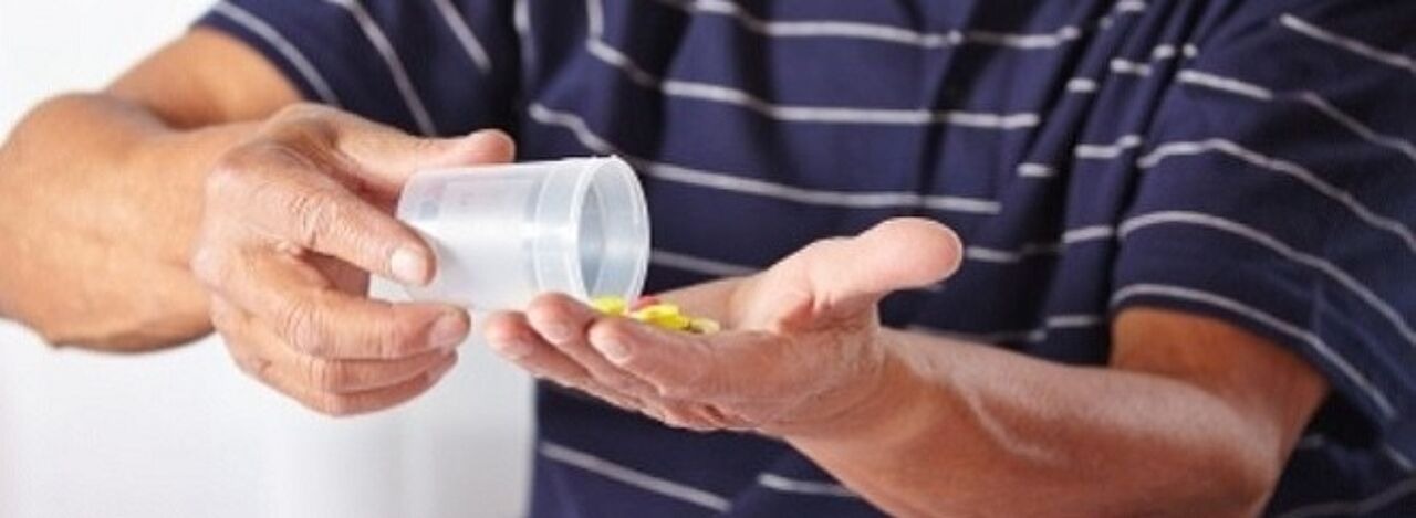 Mann schüttet sich viele tabletten auf die Hand