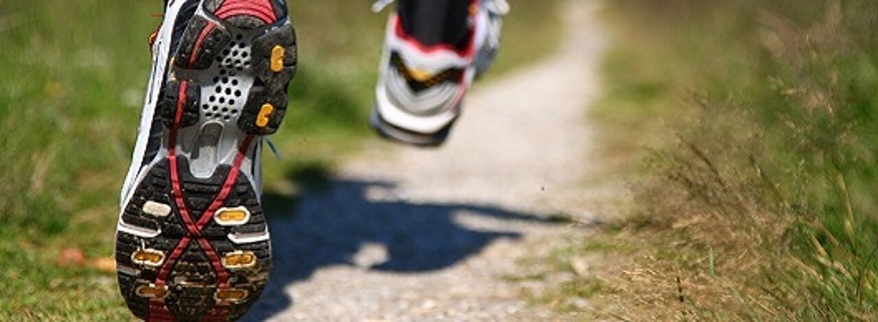 Mensch in Laufschuhen joggt schmalen Pfad