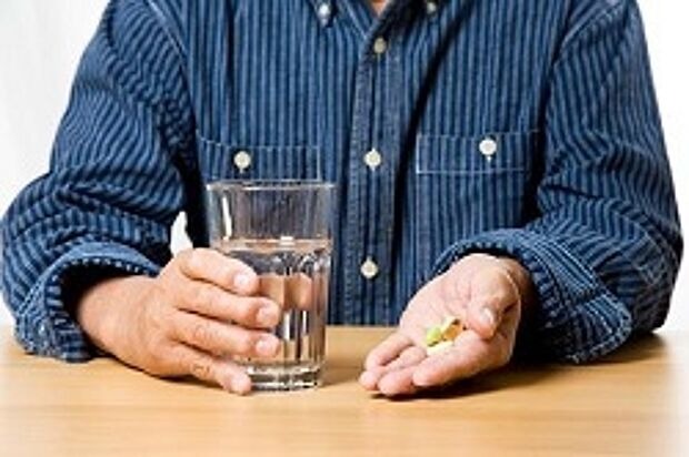 Mann mit Wasserglas und Tabletten
