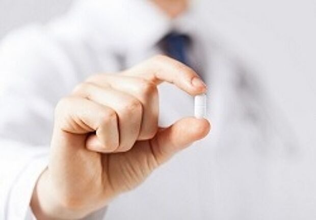 Arzt hält Tablette zwischen zwei Fingern