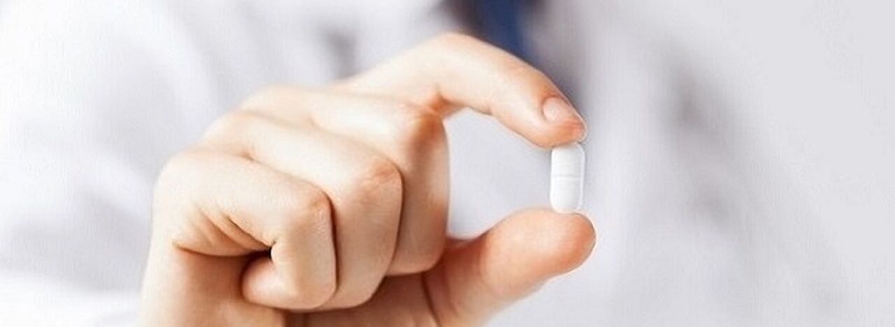 Arzt bzw. Ärztin hält Tablette zwischen zwei Fingern