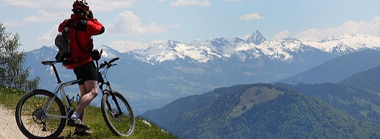 Mann mit Fahrrad blickt auf Berge